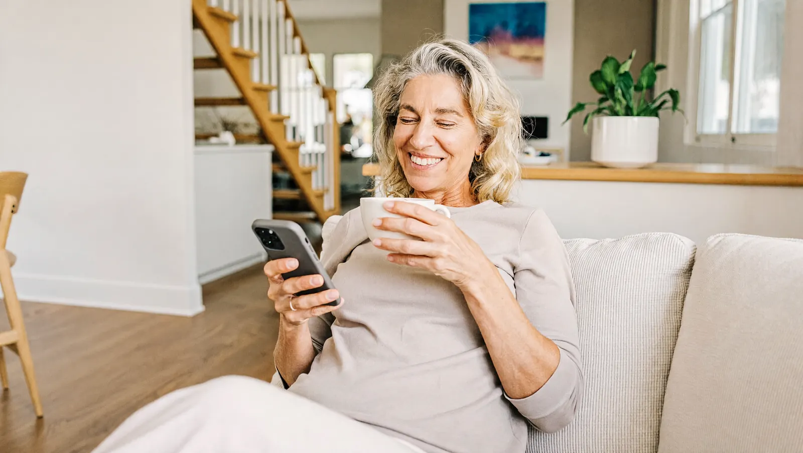 A California homeowner relaxing at home while reviewing her Home Equity Investment on her phone